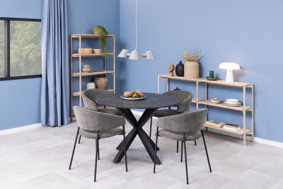 Dining room with a round table and chairs against a blue wall.