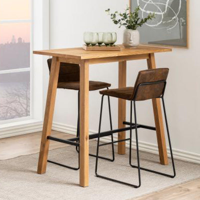 A brown rectangular Chara bar table with a metal footrest, situated in a room with a window and decorative items in the background.