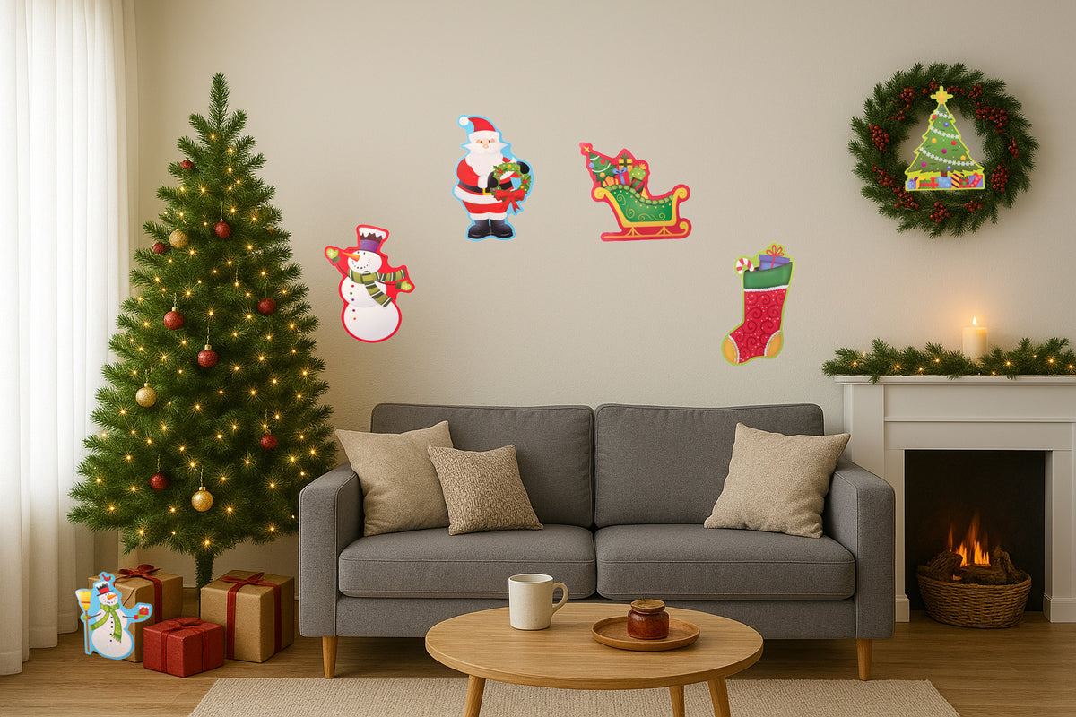 A cozy living room decorated for Christmas, featuring a gray sofa, a lit Christmas tree with ornaments and wrapped gifts, a fireplace with a green wreath, and colorful Christmas wall decals including Santa, a snowman, a sleigh, and stockings.