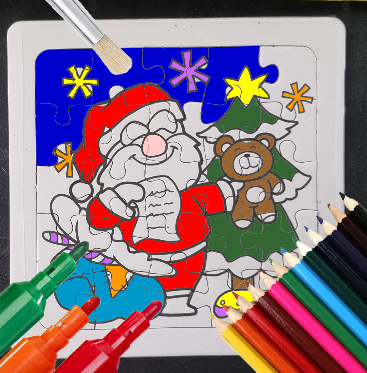 A festive coloring puzzle featuring Santa Claus, a teddy bear, and a Christmas tree, shown with paint markers and colored pencils on a dark background.