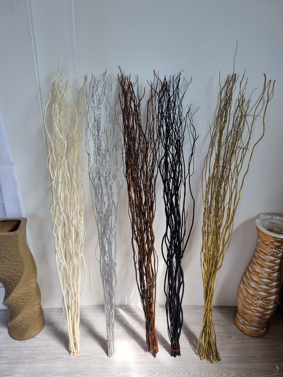 5 bunches of willow twigs next to floor vases in a living room