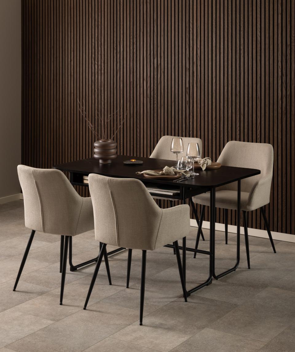 Dining room setup with a black table and beige chairs against a striped wall.