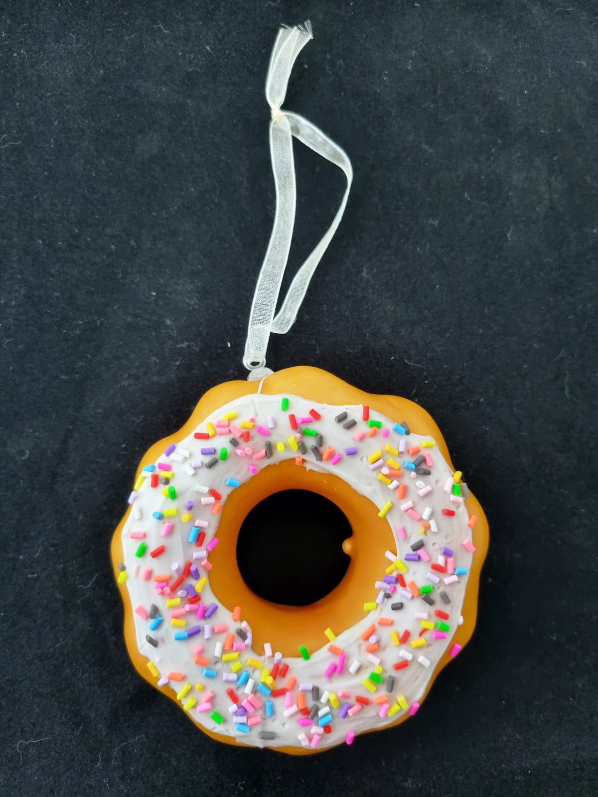 a novelty plastic doughnut with ribbon on a black textured background