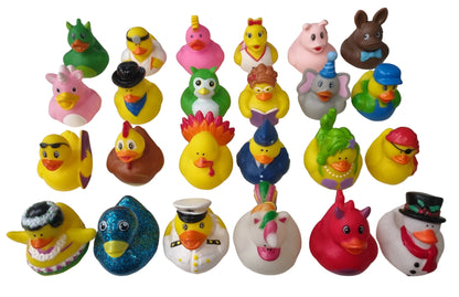 A random collection of colorful rubber duck toys arranged in rows on a white surface. The set includes various duck characters in different costumes, colors, and expressions, such as a green dinosaur, a pink unicorn, a blue glitter duck, and a white snowman duck.