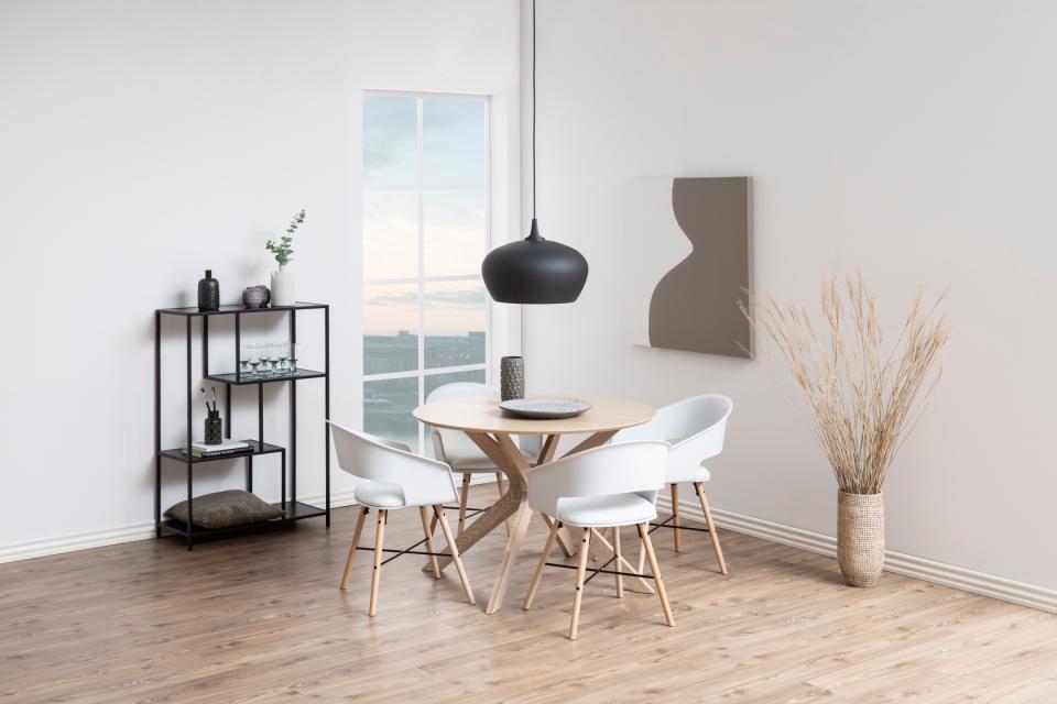 Modern dining area with a round wooden table and white chairs in a bright room.