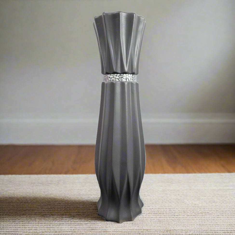 A large grey ceramic floor standing vase with a stripe detail, placed on a carpeted floor against a neutral background.
