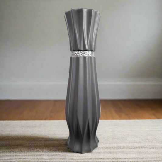 A large grey ceramic floor standing vase with a stripe detail, placed on a carpeted floor against a neutral background.