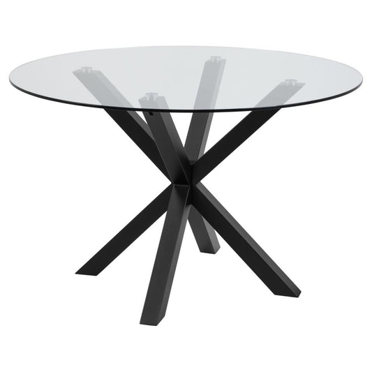A large round dining table with a clear glass top and a solid matt black metal cross base with angular legs.