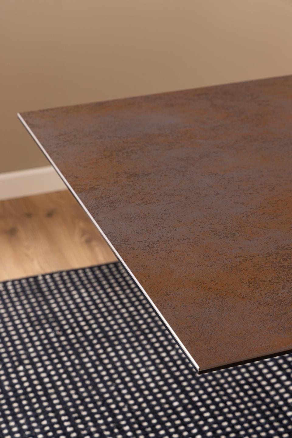 Brown ceramic table on a checkered rug with a neutral background