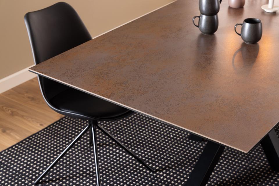 Dining table with a brown ceramic top and black chair on a wooden floor.