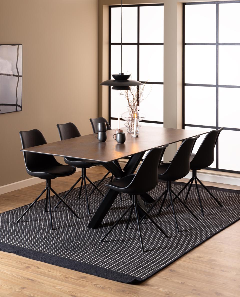 Dining room with a ceramic table and black chairs on a dark rug.