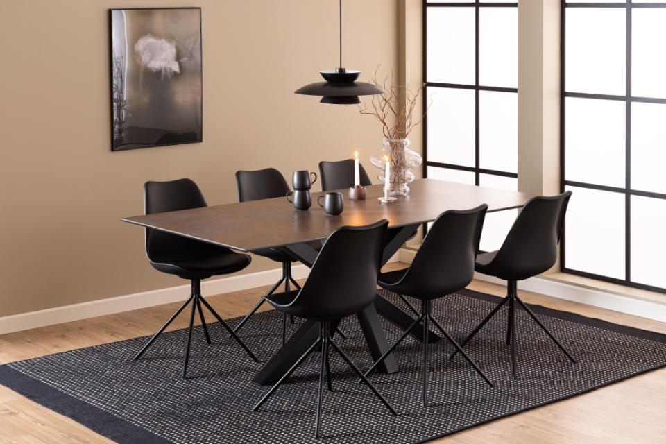 Dining room with a wooden table and black chairs on a dark rug.