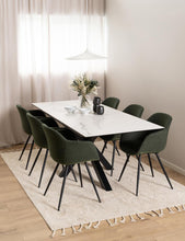 Load image into Gallery viewer, A modern dining room setup featuring a rectangular white marble-top table surrounded by six dark green upholstered chairs with black metal legs, set on a cream shag rug with a pendant light and sheer curtains in the background.
