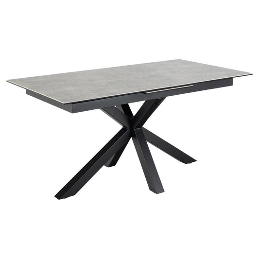 A modern extendable grey dining table with a ceramic top and a black metal cross base with the extension closed.