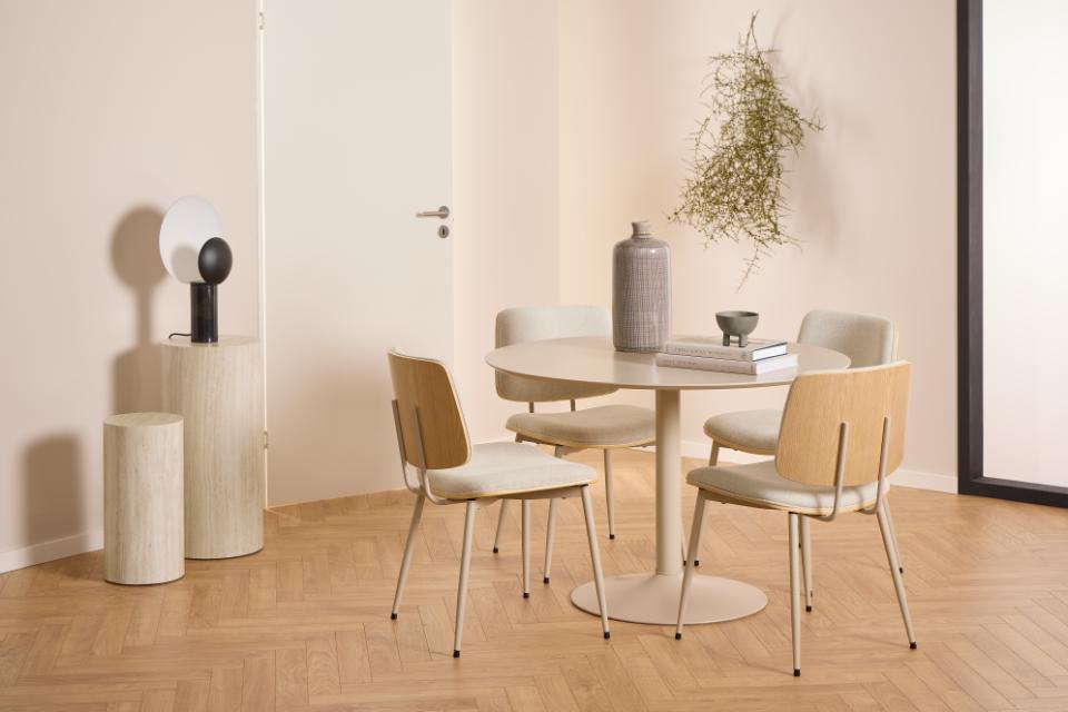 Modern dining area with a round table and chairs in a minimalistic room.