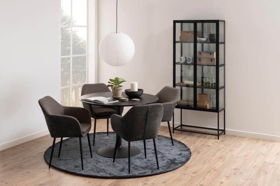 Dining room with round table and chairs, rug, and bookshelf.