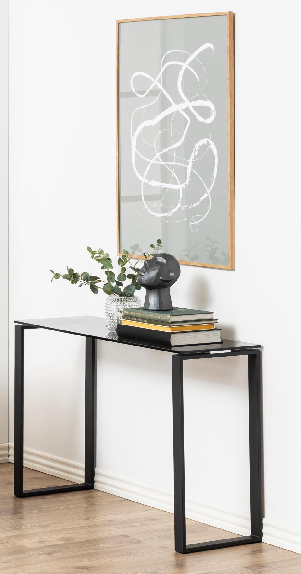 Modern console table with decorative items and abstract art on a white wall.