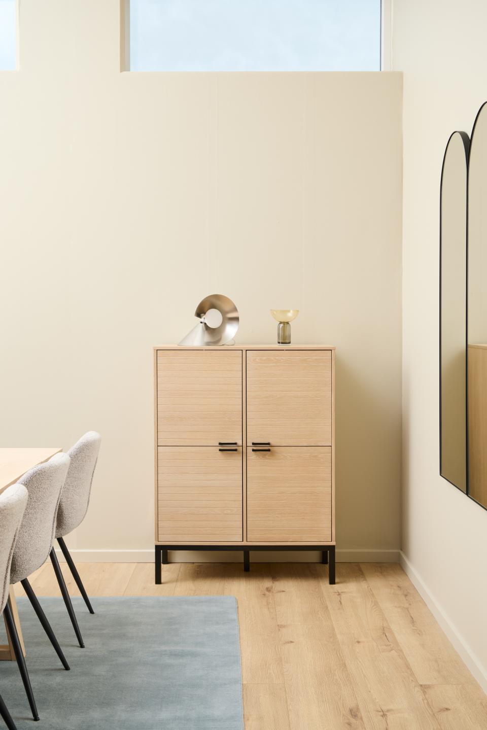 Wooden cabinet with two doors in a room with light-colored walls and wooden flooring.