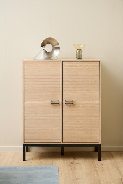 Wooden cabinet with two doors on a wooden floor against a beige wall.