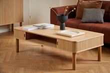 Load image into Gallery viewer, Wooden coffee table with decorative items in a living room setting
