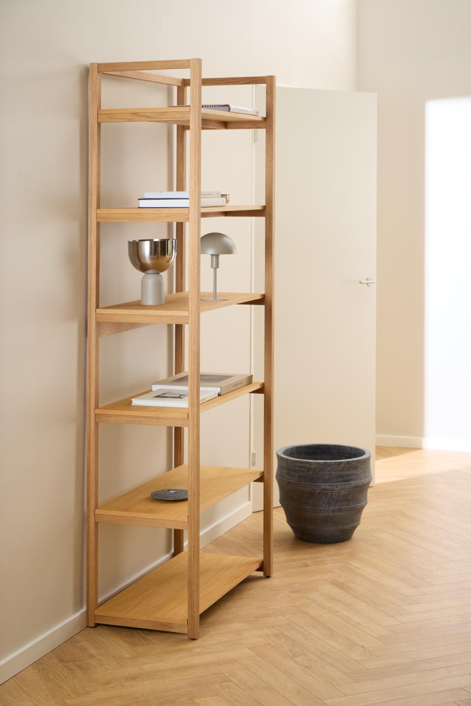 Wooden bookshelf with decorative items against a plain wall.