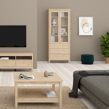 A brown light oak Madrid cabinet with two glass doors, three drawers and three shelves in a modern home with matching furniture