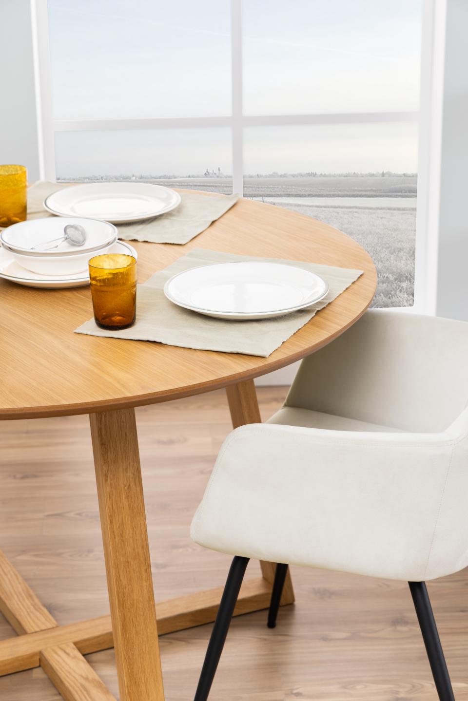 the side of a malika dining table in oak dressed for dining next to a white chair