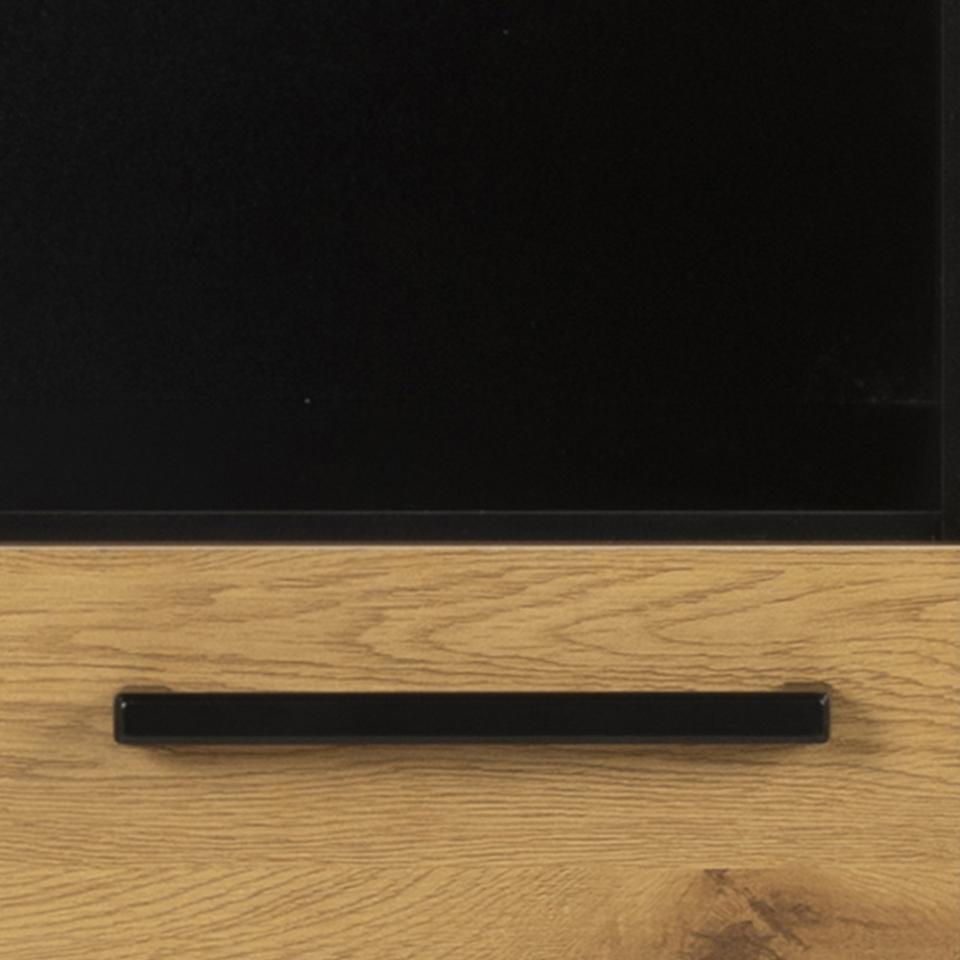 Close-up of a black horizontal drawer handle mounted on a light oak wood cabinet door with a black upper panel.