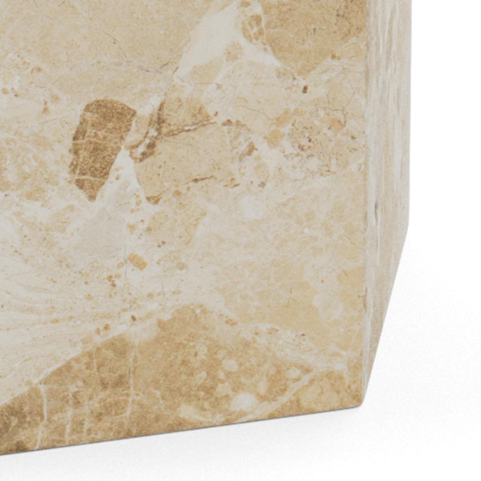 A close-up of a polished stone dining table base corner showing a warm beige and cream marbled surface with natural veining.