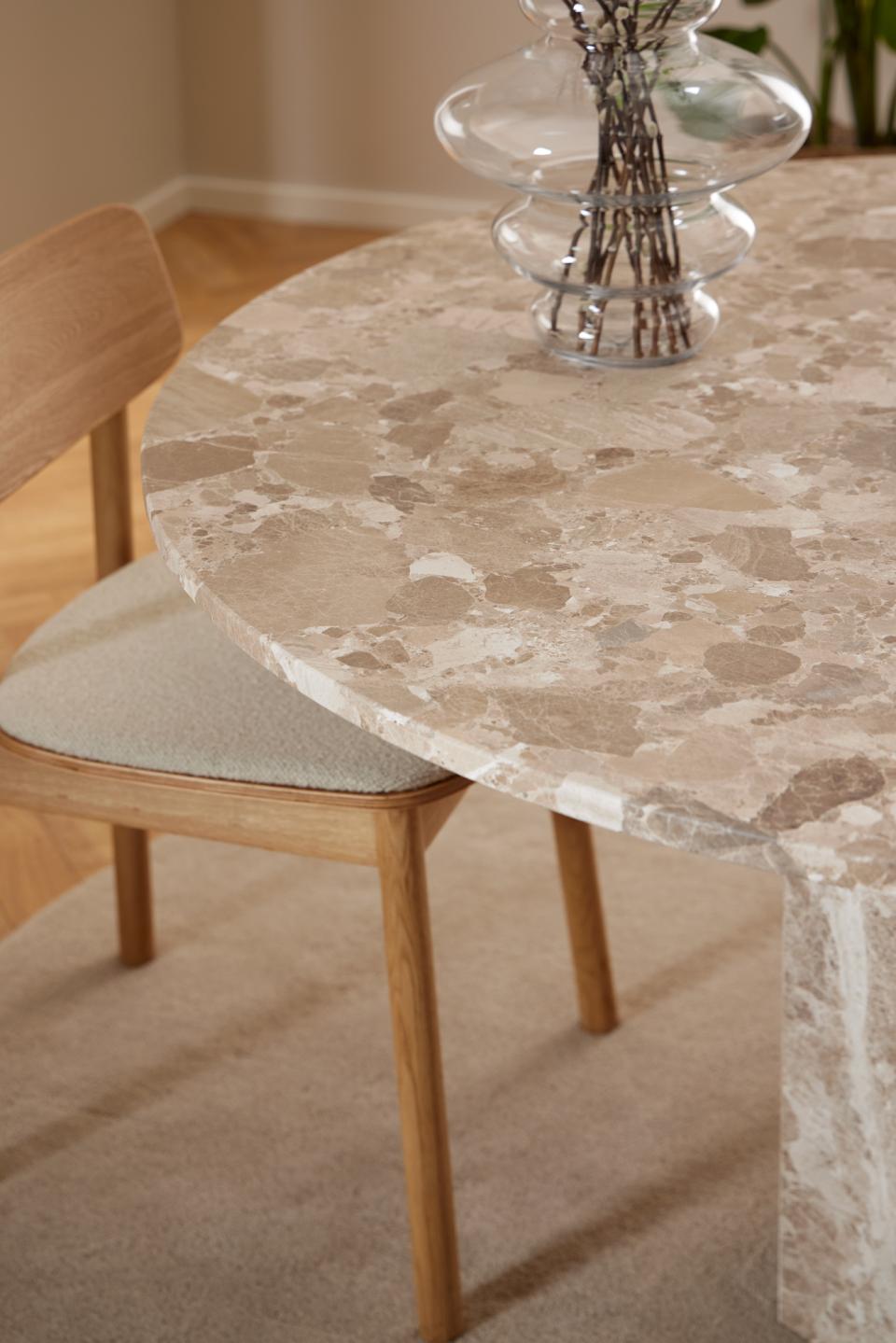Round marble dining table with wooden chair in a room setting