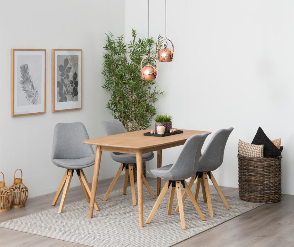 Dining room with wooden table and gray chairs, featuring a plant and decorative items.
