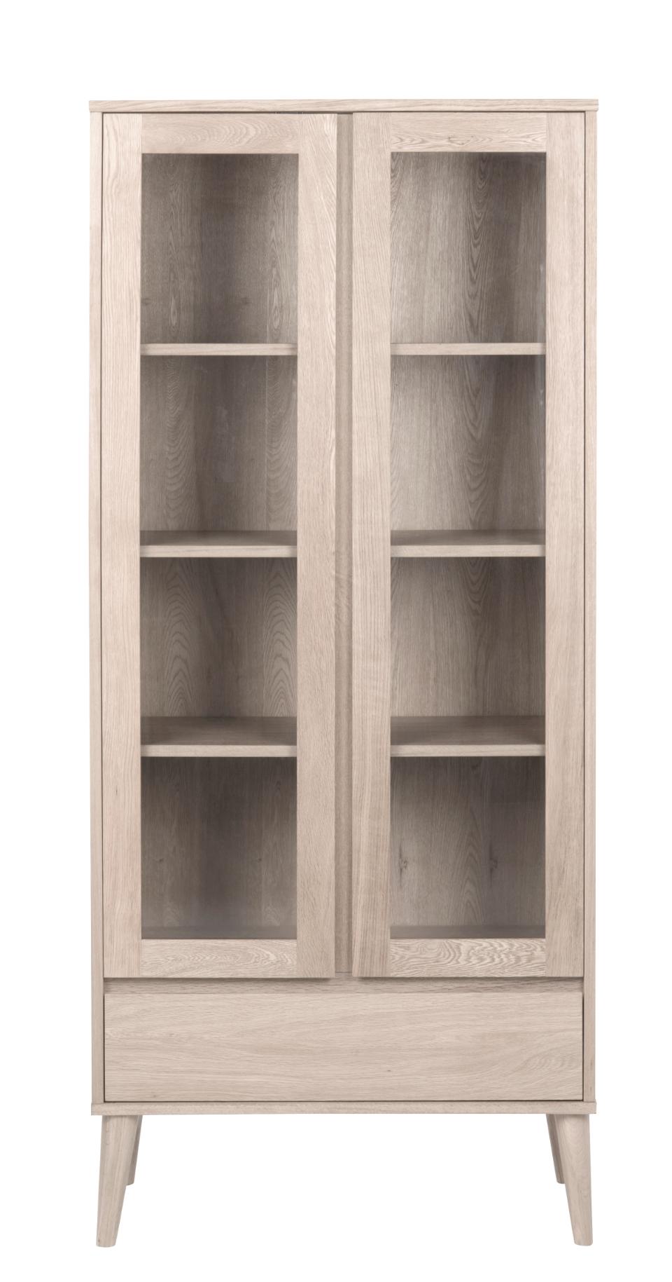 A tall, narrow light oak wood display cabinet with two glass doors, four interior shelves, and tapered legs, shown against a plain white background.
