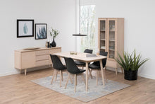 Load image into Gallery viewer, Dining room with wooden table, chairs, and sideboard in a bright room.
