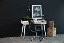 Load image into Gallery viewer, A modern home office setup featuring a light wood and white desk with tapered legs, a black slatted office chair, a black desk lamp, and a framed botanical print against a dark charcoal wall.
