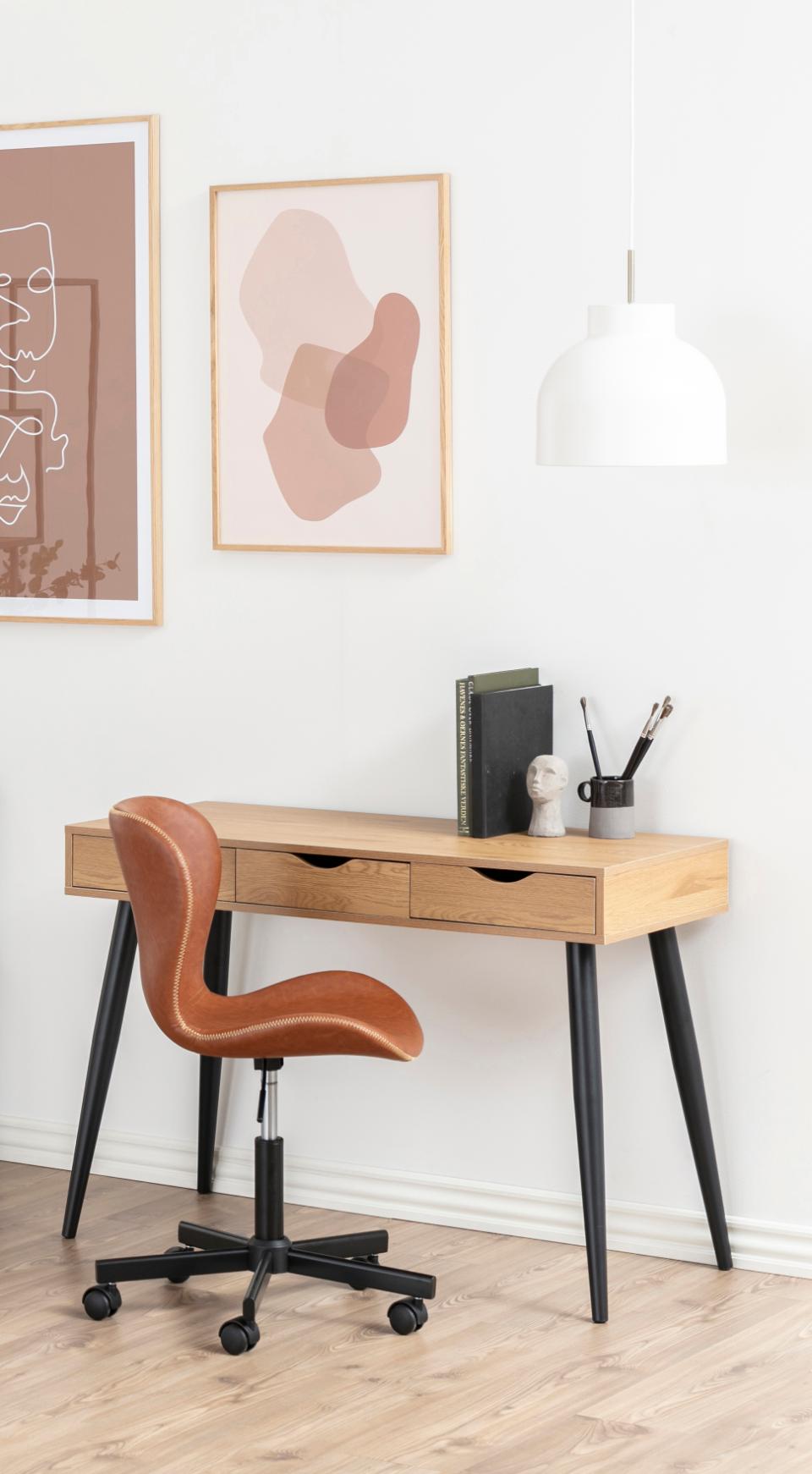 Wooden desk with a brown office chair in a room with abstract art on the wall.