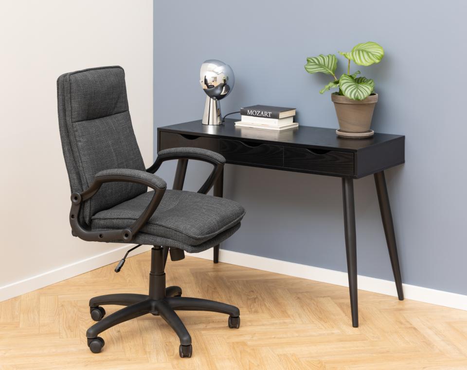 Gray office chair and black desk with decor items against a light blue wall.