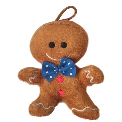 A plush gingerbread man hanging ornament or toy in brown faux fur, with a blue polka-dot bow tie, pink buttons, and white icing details on a plain white background.