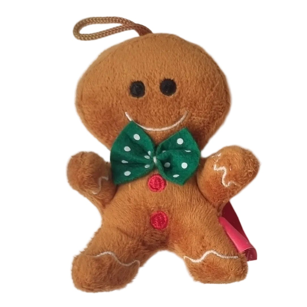 A plush gingerbread person hanging ornament or toy with a green polka-dot bow tie, red buttons, and a brown loop at the top, shown on a plain white background.