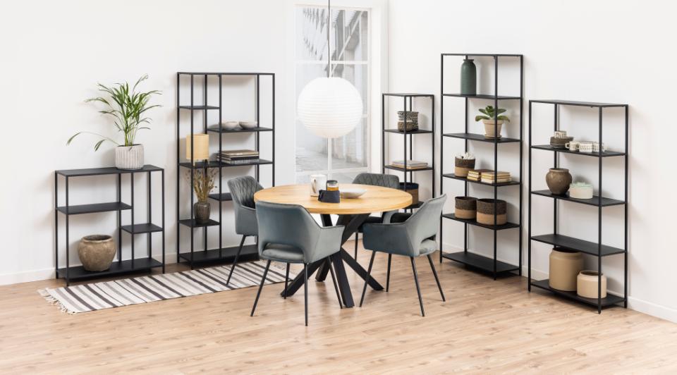 Dining room with round table and chairs, surrounded by black metal bookshelves.