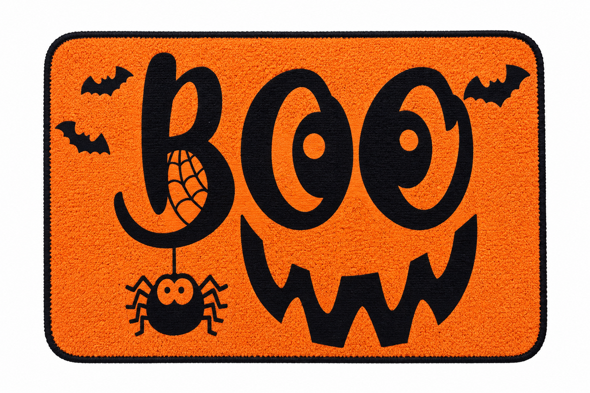 An orange rectangular doormat with rounded corners, featuring a black border and a Halloween design. The design includes the word 'BOO' in large black letters, a black jack-o'-lantern face, a black spider hanging from a web, and two black bats in the corners.