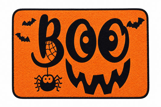 An orange rectangular doormat with rounded corners, featuring a black border and a Halloween design. The design includes the word 'BOO' in large black letters, a black jack-o'-lantern face, a black spider hanging from a web, and two black bats in the corners.