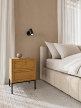 Load image into Gallery viewer, Wooden nightstand next to a beige sofa with white cushions in a bedroom setting.
