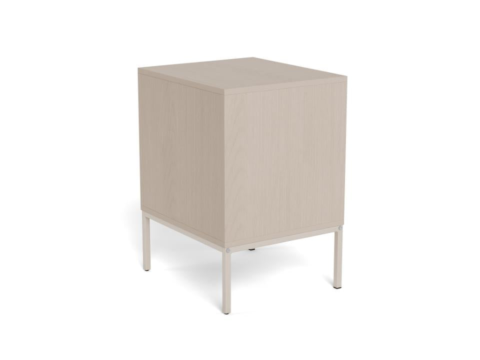 A minimalist cube-shaped side table or cabinet with a light beige wood grain finish and slim white metal legs, shown from a three-quarters angle on a white background.