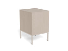 Load image into Gallery viewer, A minimalist cube-shaped side table or cabinet with a light beige wood grain finish and slim white metal legs, shown from a three-quarters angle on a white background.
