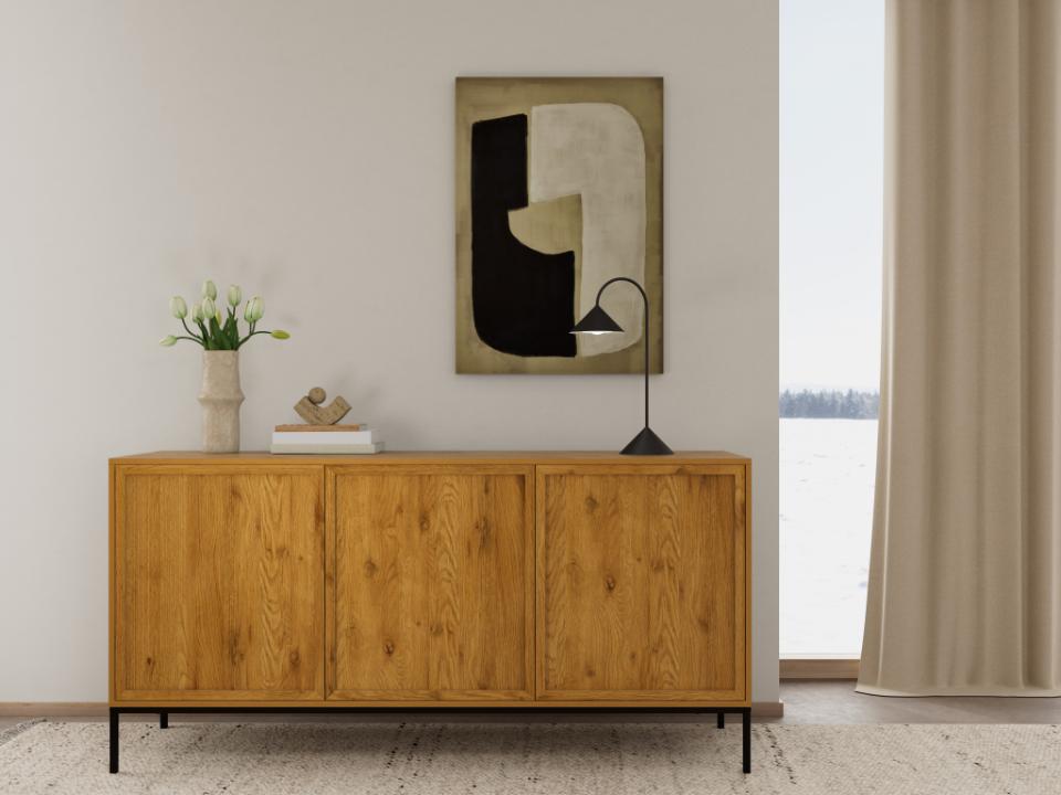 A mid-century modern wooden sideboard cabinet with black metal legs, styled in a minimalist room with a vase of flowers, books, a table lamp, and an abstract geometric wall art piece above it.