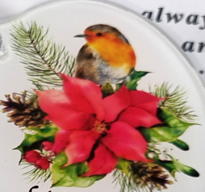 A close-up of a decorative white ceramic plate or dish featuring a robin bird perched above a large red poinsettia, green holly leaves, pine needles, and pinecones.