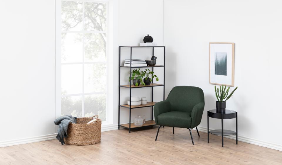 Modern living room with a green armchair, bookshelf, and side table.