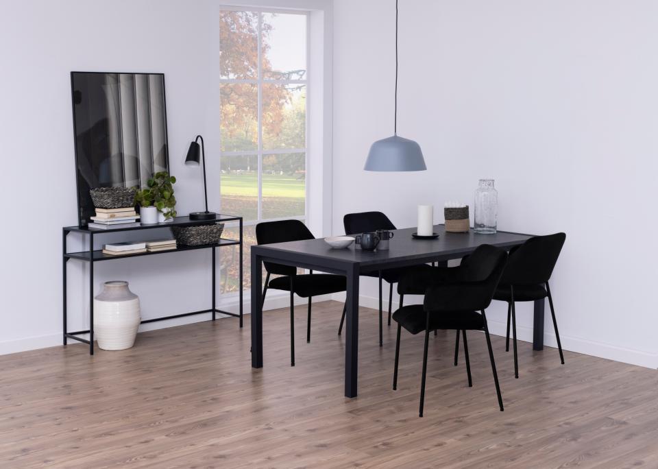 A modern dining room scene featuring a black rectangular dining table surrounded by six black chairs, with a gray pendant light overhead, set in a bright room with light wood floors and white walls.