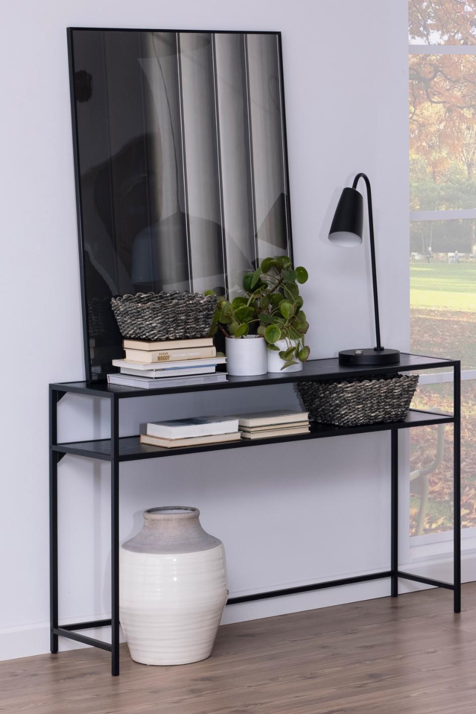 Black console table with decorative items against a white wall