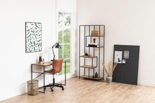 Load image into Gallery viewer, A modern home office setup in a bright room with white walls and light wood flooring, featuring a black metal desk with a brown swivel chair, a tall black shelving unit, and a large black board leaning against the wall.

